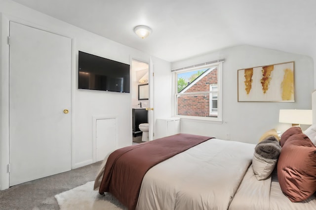 carpeted bedroom with connected bathroom and vaulted ceiling