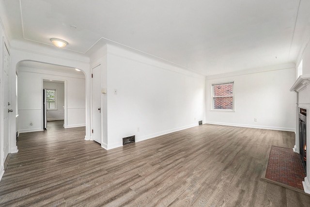 unfurnished living room featuring crown molding and dark hardwood / wood-style flooring