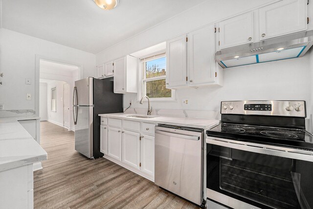 kitchen with white cabinets, sink, light hardwood / wood-style flooring, appliances with stainless steel finishes, and light stone countertops