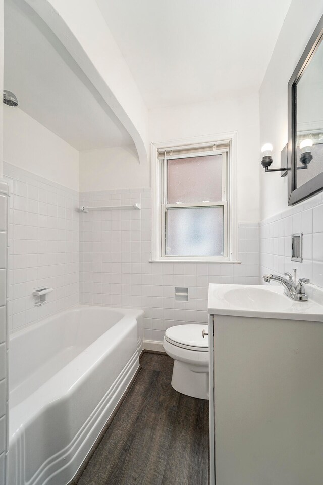 full bathroom with vanity, shower / bath combination, wood-type flooring, tile walls, and toilet