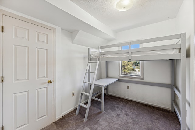 unfurnished bedroom with dark carpet and a textured ceiling