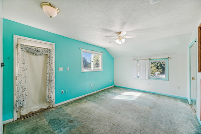 carpeted empty room featuring a textured ceiling, lofted ceiling, and ceiling fan