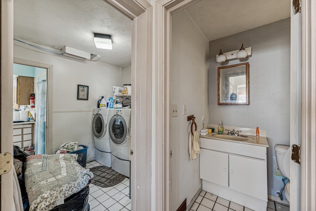 clothes washing area featuring light tile patterned floors, a textured ceiling, sink, and washing machine and dryer