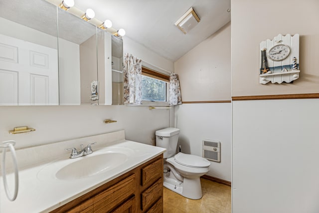 bathroom featuring heating unit, vanity, lofted ceiling, toilet, and tile patterned floors