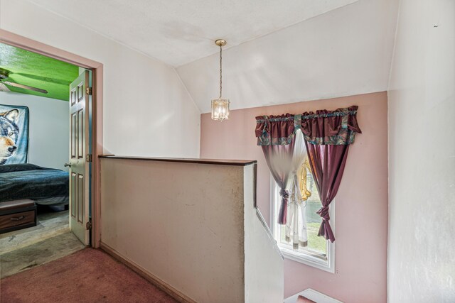 corridor with a notable chandelier, lofted ceiling, and carpet floors