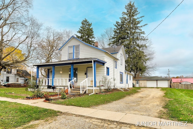 view of front of house featuring a garage, covered porch, a front yard, and an outbuilding