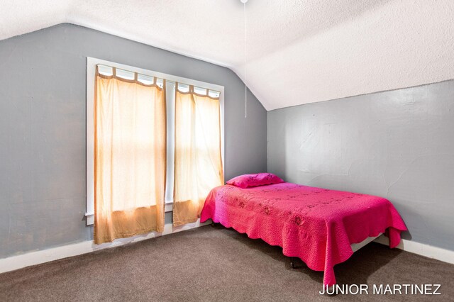 carpeted bedroom featuring a textured ceiling and vaulted ceiling