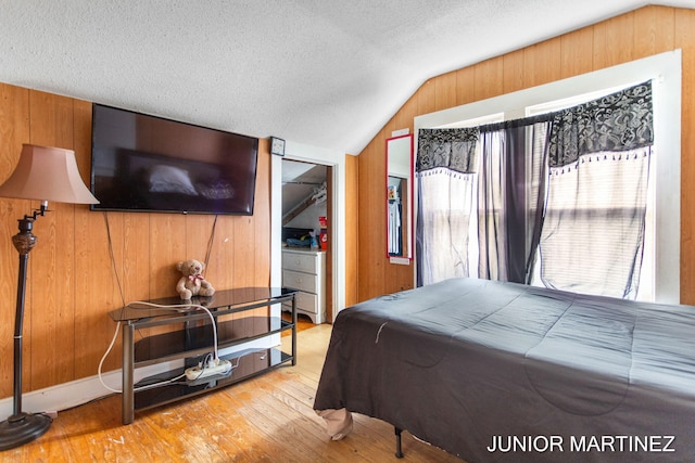 bedroom featuring wood-type flooring, vaulted ceiling, and wood walls