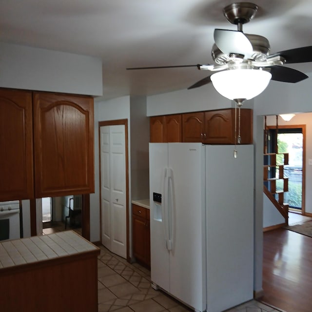 kitchen with ceiling fan, tile countertops, white appliances, and light hardwood / wood-style flooring