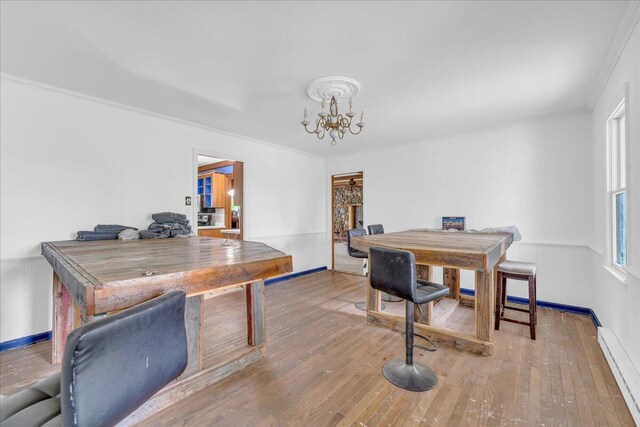 office space with hardwood / wood-style flooring, crown molding, a notable chandelier, and a baseboard heating unit