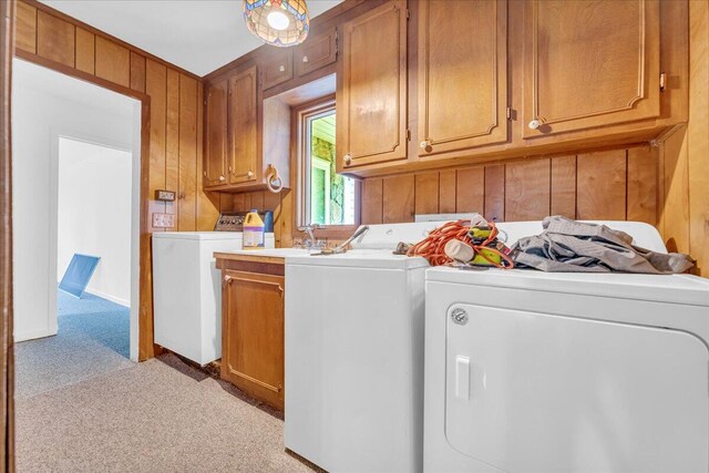 laundry room with cabinets, wooden walls, light colored carpet, and washer and clothes dryer