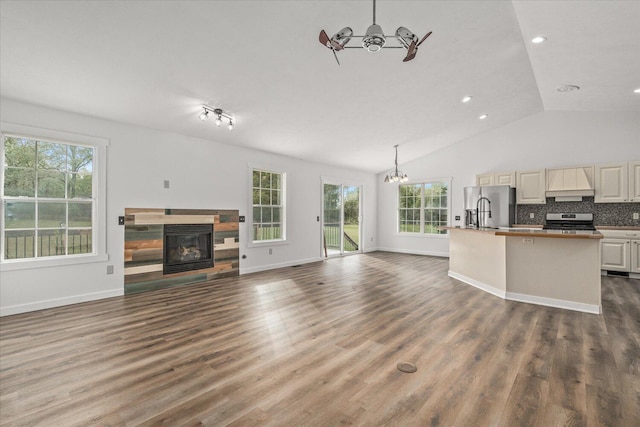 unfurnished living room with an inviting chandelier, vaulted ceiling, and dark hardwood / wood-style floors