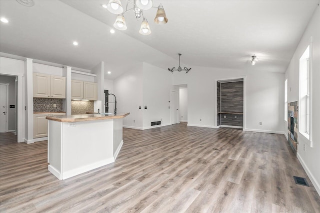 kitchen with light wood-type flooring, vaulted ceiling, an inviting chandelier, and pendant lighting