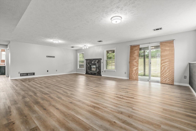 unfurnished living room featuring a textured ceiling, a fireplace, and light hardwood / wood-style floors