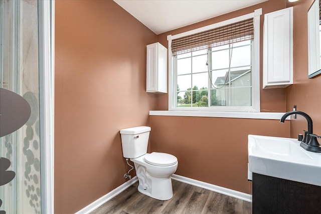 bathroom with hardwood / wood-style floors, lofted ceiling, vanity, and toilet