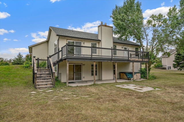 back of property with a yard, a wooden deck, and a patio area