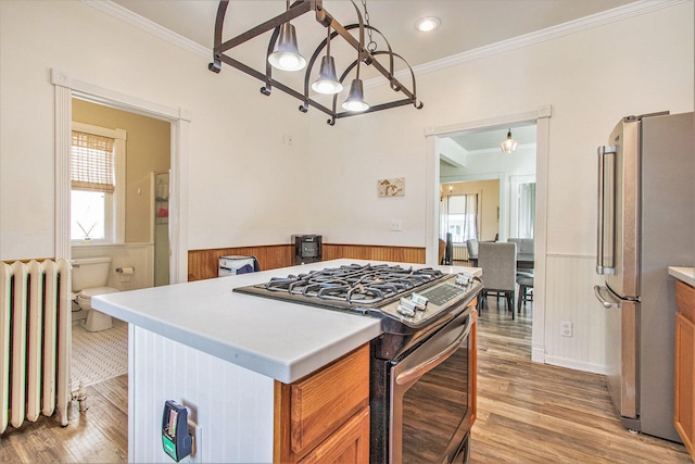 kitchen featuring radiator heating unit, a wealth of natural light, appliances with stainless steel finishes, and decorative light fixtures