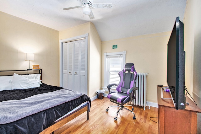 bedroom with radiator heating unit, a closet, hardwood / wood-style flooring, and ceiling fan