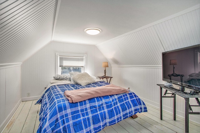 bedroom with light wood-type flooring, lofted ceiling, and wood walls