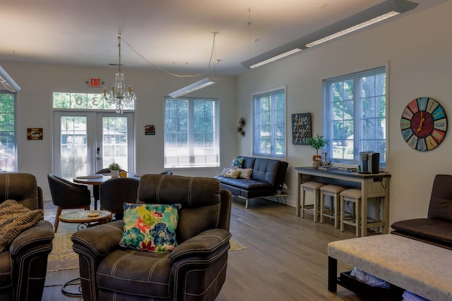 living room featuring a notable chandelier, wood-type flooring, and french doors