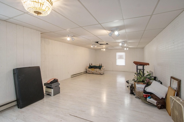 living area with wood-type flooring, a baseboard heating unit, and a paneled ceiling