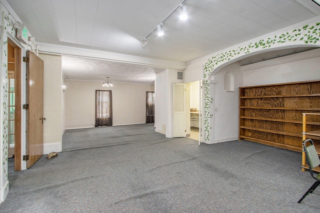 unfurnished room featuring a notable chandelier, track lighting, carpet flooring, and crown molding