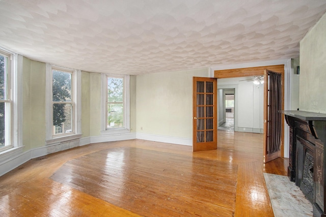 unfurnished living room with light wood-type flooring, a healthy amount of sunlight, and a high end fireplace