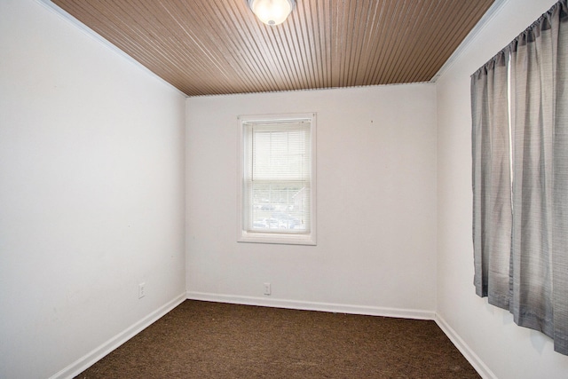 spare room with crown molding, wood ceiling, and dark colored carpet