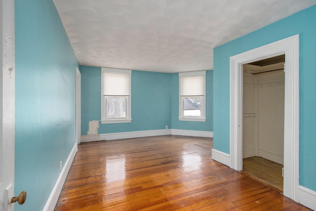 unfurnished bedroom with a spacious closet, a closet, and hardwood / wood-style floors