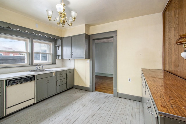 kitchen featuring pendant lighting, white dishwasher, sink, light wood-type flooring, and butcher block counters