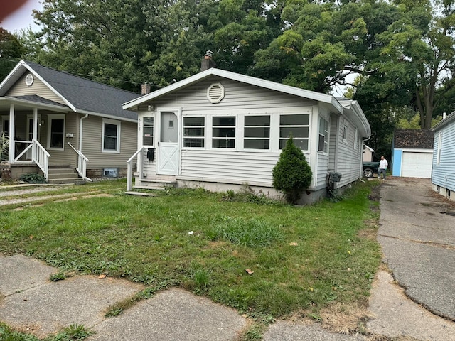 view of front of property featuring a garage, an outdoor structure, and a front lawn