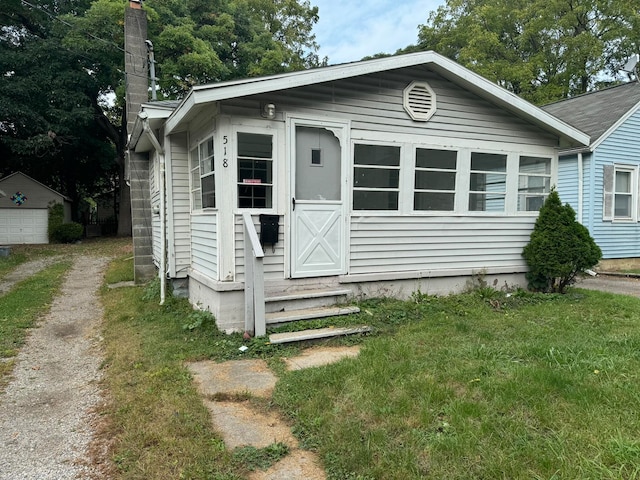 bungalow with a front lawn and an outbuilding