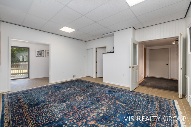 empty room with a drop ceiling and tile patterned flooring