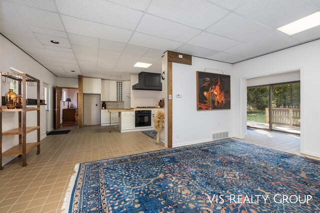 unfurnished living room with light tile patterned floors and a paneled ceiling