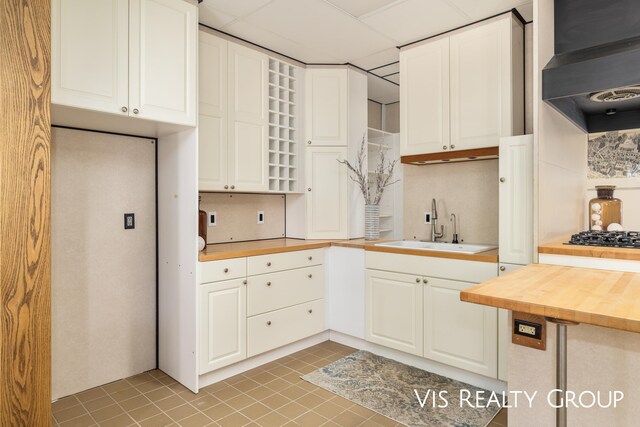 kitchen with sink, white cabinetry, decorative backsplash, light tile patterned floors, and gas stovetop