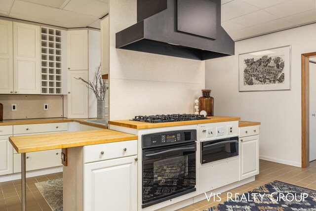 kitchen featuring dark tile patterned floors, butcher block countertops, oven, extractor fan, and stainless steel gas stovetop