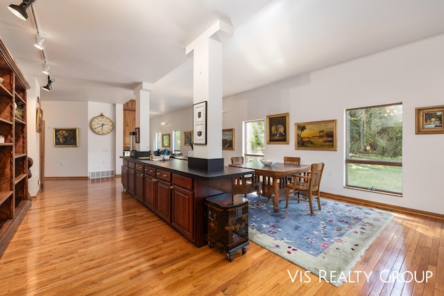 kitchen featuring dark brown cabinetry, a breakfast bar area, light wood-type flooring, and rail lighting