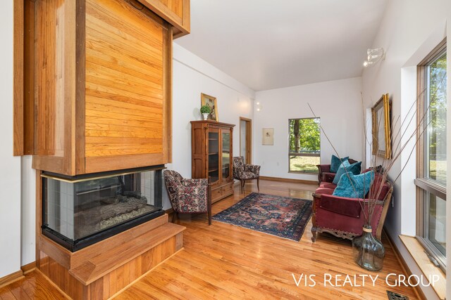 living room with a multi sided fireplace, hardwood / wood-style floors, and a healthy amount of sunlight