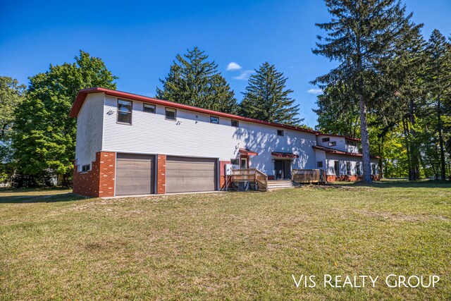 view of front of house with a front yard, a garage, and a wooden deck