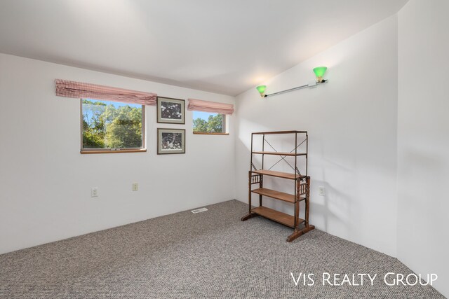 carpeted empty room with vaulted ceiling