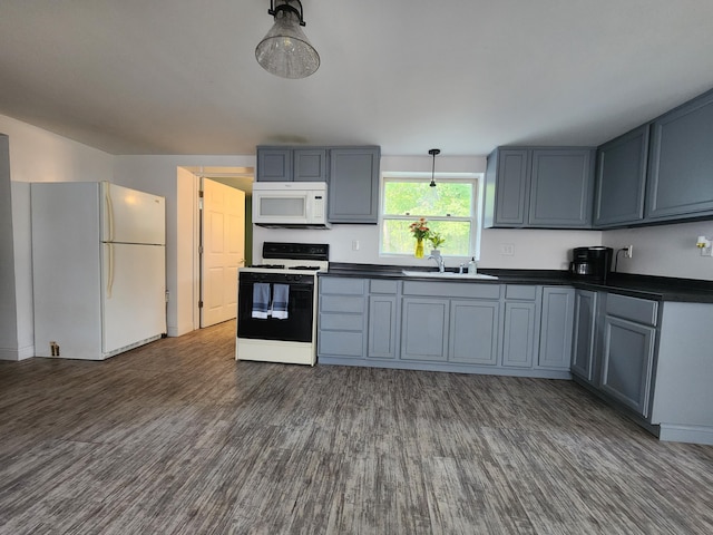 kitchen with dark wood-type flooring, hanging light fixtures, sink, and white appliances