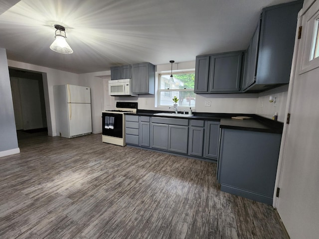 kitchen featuring hanging light fixtures, sink, white appliances, gray cabinetry, and dark wood-type flooring