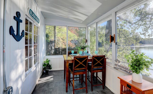 sunroom featuring a water view