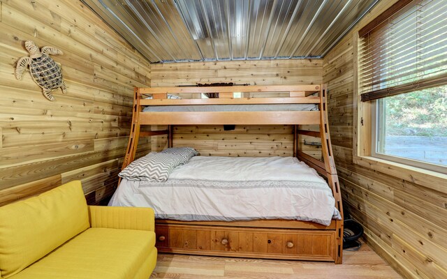 bedroom with wooden walls, wood ceiling, and light hardwood / wood-style flooring