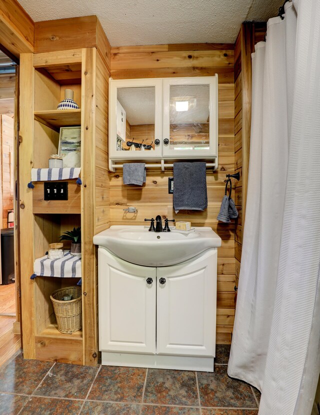 bathroom featuring vanity, a textured ceiling, and wood walls