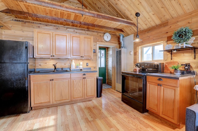 kitchen with hanging light fixtures, wooden walls, black appliances, and light wood-type flooring