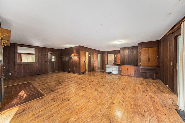 unfurnished living room with light wood-type flooring and wooden walls