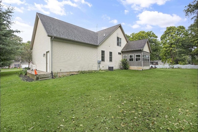 rear view of property with central AC unit and a yard