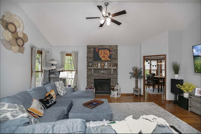 living room with lofted ceiling, a stone fireplace, dark wood-type flooring, and ceiling fan