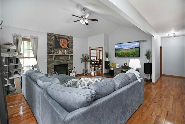 living room with wood-type flooring, vaulted ceiling, ceiling fan, and a fireplace